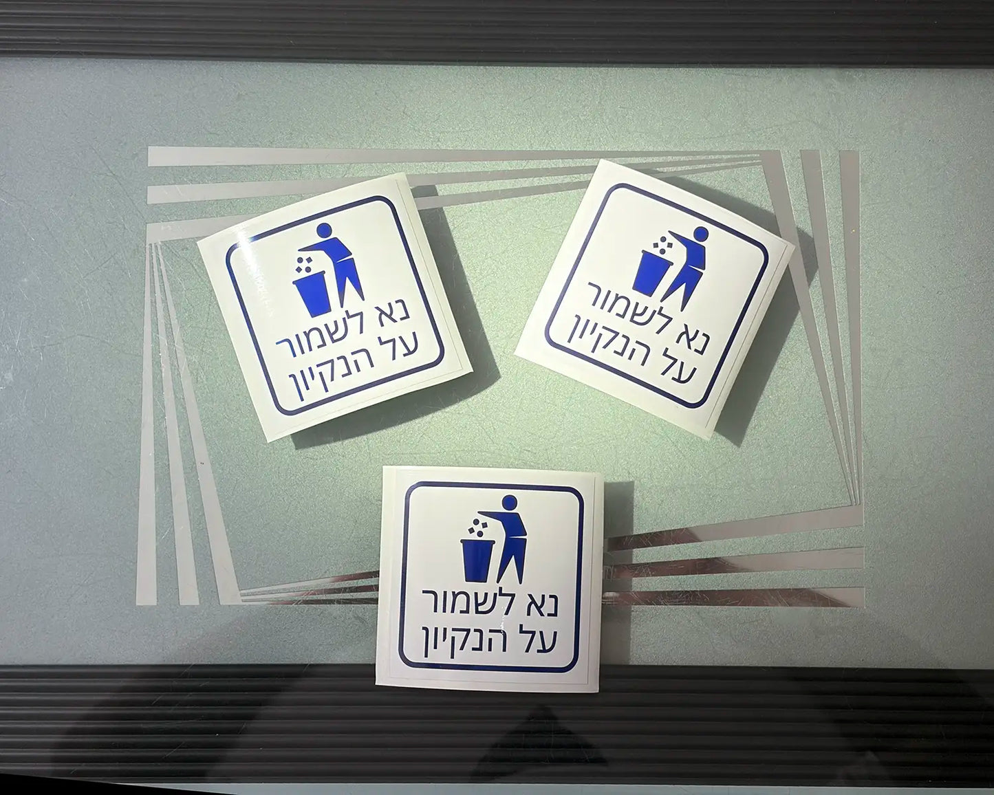 סט מדבקות קטנות בעיצוב אישי של Adboy עם הכיתוב 'נא לשמור על ניקיון', מודבקות בתוך מעלית מודרנית