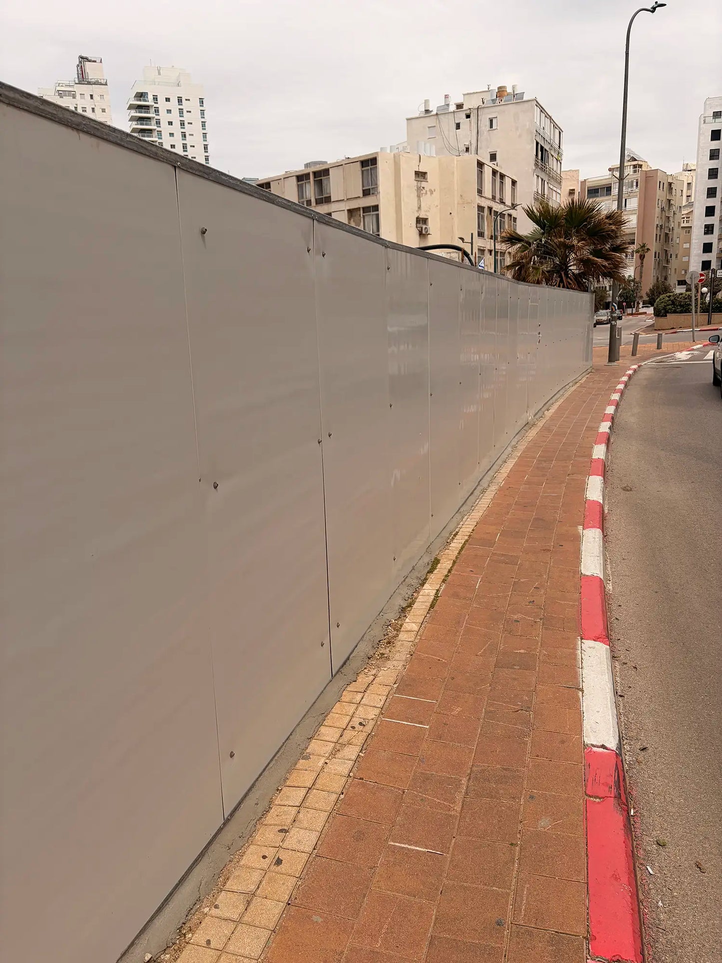 תקריב צדדי על פנלים של גדר איסכורית מתכתית באתר בנייה, המציג את המשטח הנקי לפני התקנת שילוט פרסום בפורמט רחב