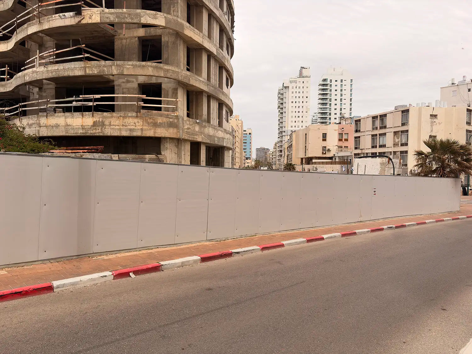 גדר איסכורית אפורה ורגילה המקיפה אתר בנייה פעיל בנתניה, לפני ביצוע מיתוג היקפי או הדבקת מדבקות ויניל