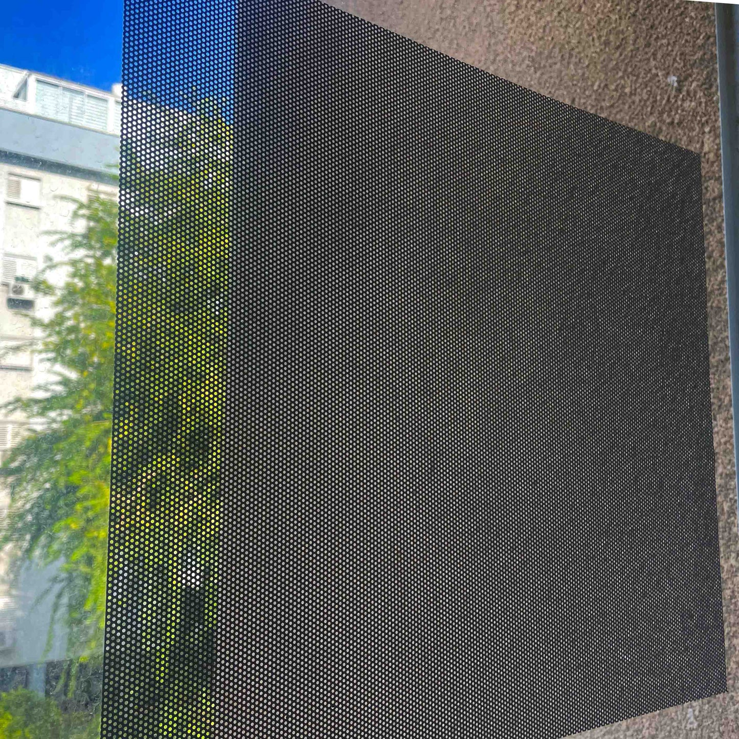 מדבקת רשת שקופה למחצה על חלון, מאפשרת לראות את הנוף מבחוץ